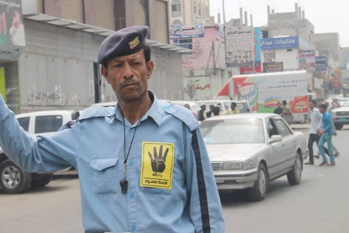 رجل مرور يمني يعلق إشارة النصر “رابعة العدوية”